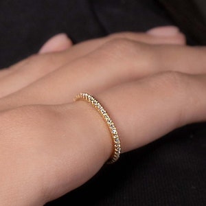 Op de afbeelding: Een dunne gouden ring met kleine heldere stenen die in de band zijn gezet.