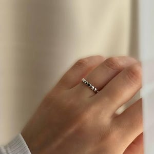 May include: A silver ring with a beaded design. The ring is made of small, round beads that are evenly spaced.