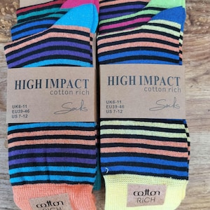 Pode incluir: Dois pares de meias listradas coloridas com o texto "HIGH IMPACT cotton rich" na embalagem. As meias apresentam listras horizontais em várias cores, incluindo laranja, azul, roxo e preto. A embalagem também indica os tamanhos UK6-11, EU39-46 e US 7-12.