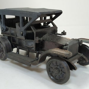 May include: A vintage-style black metal toy car with a black canvas top. The car has a detailed design with a grille, headlights, and wheels.
