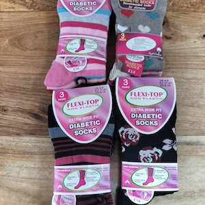 May include: Four packs of Flexi-Top non-elastic diabetic socks in various designs. One pack features pink and blue stripes, one has grey with hearts, one has black with maroon stripes, and one has black with a floral pattern. Each pack contains three pairs.