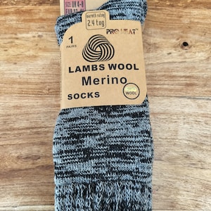以下が含まれることがあります： グレーと黒のラムウールメリノウールソックスのペア。タグには「Lambs Wool Merino Socks」と「Pro Heat」と書かれています。靴下のサイズはUK 4-8です。