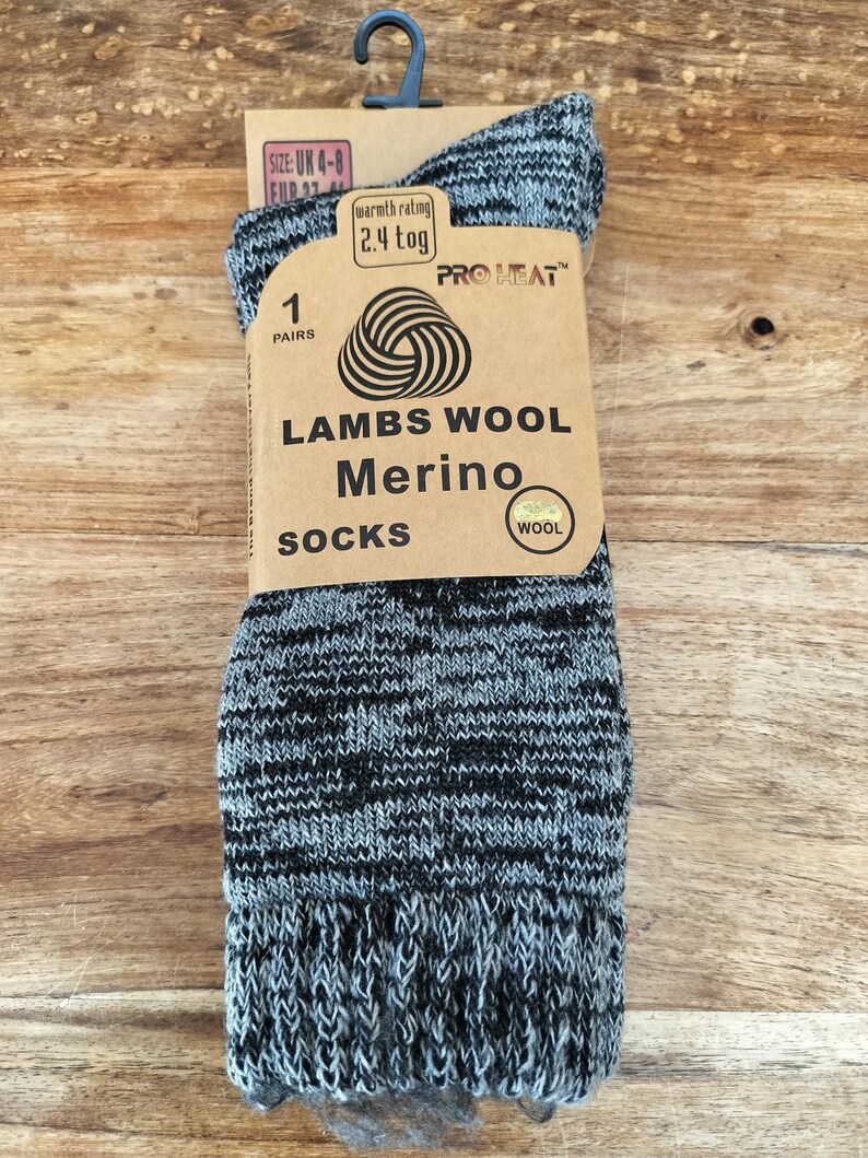 以下が含まれることがあります： グレーと黒のラムウールメリノウールソックスのペア。タグには「Lambs Wool Merino Socks」と「Pro Heat」と書かれています。靴下のサイズはUK 4-8です。