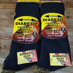 May include: Two pairs of black diabetic socks with yellow and gold accents. Each pair has a yellow and red label that reads "Diabetic Friendly Wide Top Heavy Duty Thick Cushion." The socks are size UK 6-11, EU 39-45.