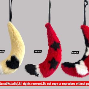 May include: Three plush tails in yellow, red, and red with black and white accents, each suspended by a black strap. The tails are labelled "Yellow D", "Red D", and "Red E". The bottom of the image has text.