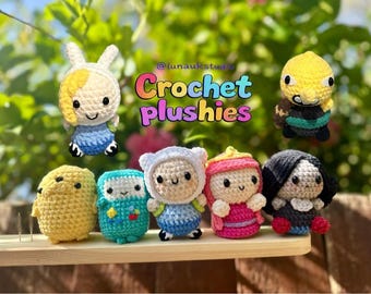 Könnte beinhalten: Eine Sammlung farbenfroher Häkeltier-Plüschtiere, darunter Charaktere mit gelben, blauen und rosa Outfits. Der Text "Crochet plushies" ist in Regenbogenfarben dargestellt. Die Plüschtiere sind auf einem Holzregal ausgestellt.