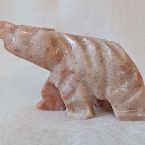 May include: A hand-carved pink and white alabaster sculpture of a bear standing on all fours.