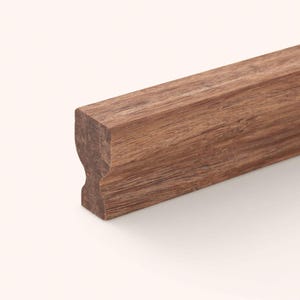 May include: A long, straight piece of brown wood molding with a distinct profile. The cross-section shows a curved, indented shape on the side, while the wood grain is visible along the length of the piece, showcasing a natural, dark brown tone.