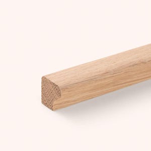 May include: A light brown wooden molding strip with a natural wood grain texture. The piece features a square profile on one side and a rounded, curved edge on the other, showcasing the raw, unfinished surface of the timber material.