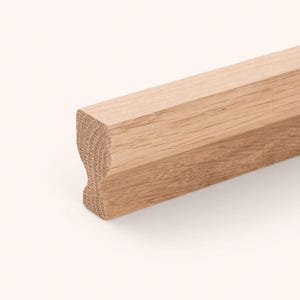 May include: A light brown wooden molding strip with a natural grain pattern. The piece features a distinct profile with a curved indentation along one side, showcasing the raw texture and light tan color of the unfinished wood material.