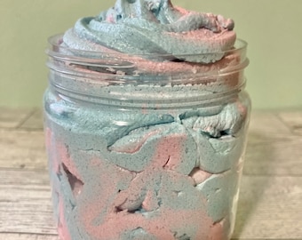 May include: A clear glass jar filled with a swirl of light blue and pink whipped body butter.