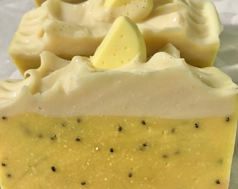 May include: Three bars of handmade soap with a lemon scent. The soap is white with a yellow lemon slice on top. The bottom layer of the soap is a light yellow with black poppy seeds.