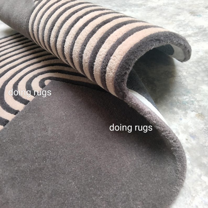 May include: Close-up of a brown and beige striped rug with a curved edge. The rug has a soft, plush texture. The text "doing rugs" is visible in the image.