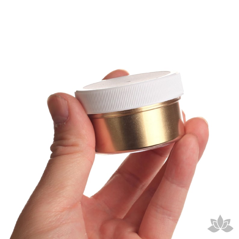 May include: A small white jar with a gold lid filled with gold glitter.