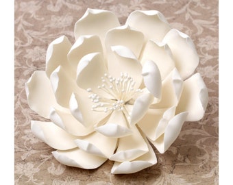May include: A large, white, artificial flower with multiple petals and a center made of small white beads.