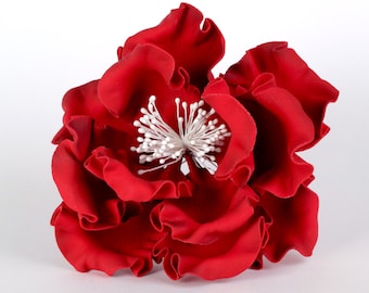 May include: A red fabric flower with ruffled petals and a white center.