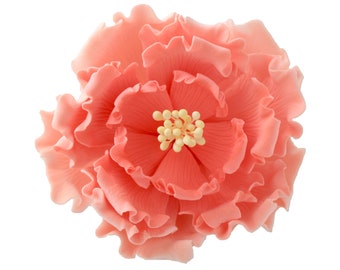 May include: A coral-colored, layered flower with ruffled petals and a cluster of yellow stamens at the center. The flower has a delicate, realistic appearance, likely a decorative element for crafts or cake decorating.