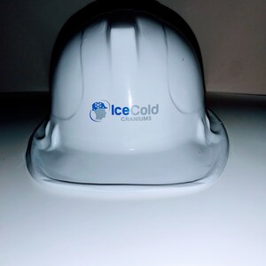 May include: White hard hat with a blue and white logo that says "IceCold Craniums".