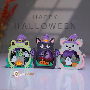 Könnte beinhalten: Drei mehrschichtige Papierdekorationen mit einem hellgrünen Frosch, einer schwarzen Katze mit violetten Flügeln und einer grauen Maus, die jeweils einen violetten Hexenhut tragen. Die Ausschnitte zeigen Halloween-Szenen mit Geistern und Kürbissen.