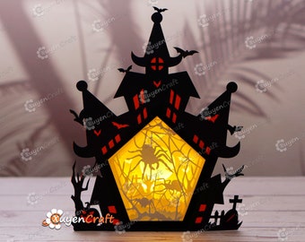 May include: Black Halloween-themed paper cut-out of a haunted house with bats, spiders, and a web design. The house has a glowing yellow interior, and a graveyard is visible in the front. The design is intricate and detailed.