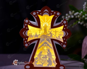 May include: A white paper cross with a red border, illuminated from within, depicting the nativity scene and the crucifixion of Jesus. The cross is a 3D paper craft with intricate details.