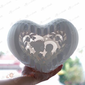 May include: White papercraft heart shaped lamp with a silhouette of a mother and child inside. The lamp is decorated with flowers and hearts.
