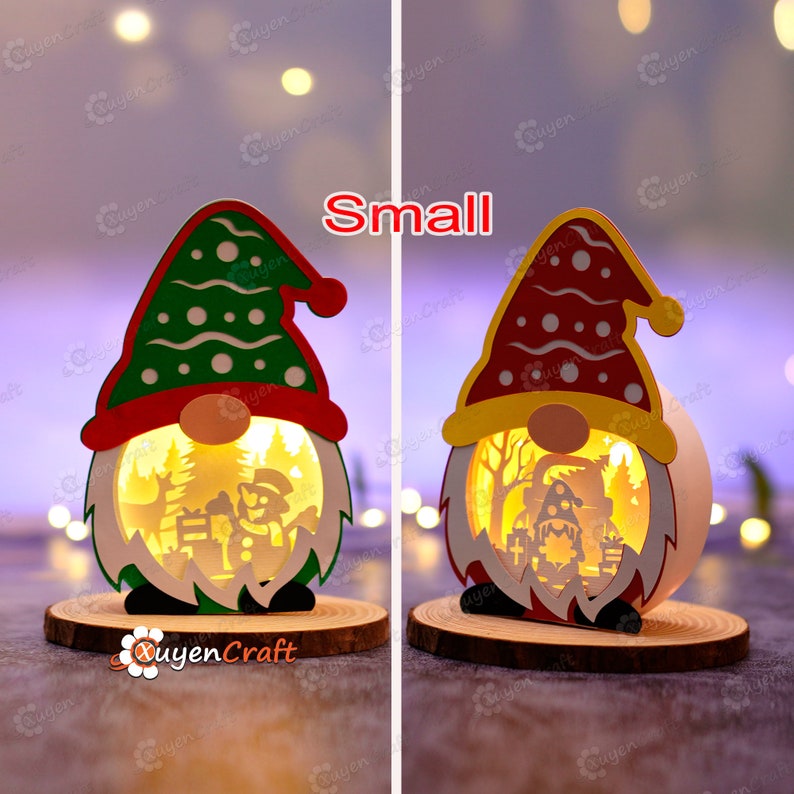 Pode incluir: Duas pequenas decora&ccedil;&otilde;es de gnomos de Natal iluminadas. Um gnomo tem um chap&eacute;u verde com bolinhas brancas, o outro um chap&eacute;u vermelho com bolinhas brancas. Ambos t&ecirc;m uma base de madeira e um design recortado mostrando uma cena de inverno. A palavra "Small" est&aacute; acima dos gnomos.
