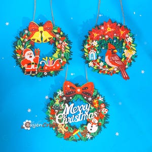 May include: Three circular Christmas wreaths featuring green foliage, red bows, and festive icons. One has Santa and a sleigh, one features a red cardinal bird with poinsettias, and the third displays the text Merry Christmas with a snowman.