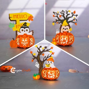 Könnte beinhalten: Drei Halloween-Papierlaternen. Jede Laterne ist orange und hat die Form eines Kürbisses mit ausgeschnittenen Mustern. Eine zeigt eine Eule, eine andere einen Igel und die letzte ein Gespenst. Sie sind mit Herbstblättern und Bäumen dekoriert.