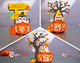 May include: A collection of three Halloween-themed paper lanterns. Each lantern is orange and shaped like a pumpkin, with cut-out designs. One features an owl, another a hedgehog, and the last a ghost. The lanterns are decorated with fall leaves and trees.