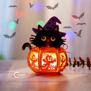 Peut inclure: Un chat noir portant un chapeau de sorcière violet est assis dans une lanterne de citrouille orange avec un motif de fantôme. La lanterne est éclairée de l'intérieur, créant une lueur chaleureuse. Il y a des chauves-souris qui volent autour de la lanterne.