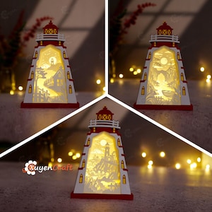 May include: A decorative wooden lighthouse lamp featuring a red and white exterior with a cutout design. The interior is illuminated, showcasing layered silhouettes of coastal scenes including houses, trees, boats, and rocky cliffs under a moon.