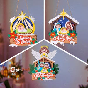 May include: Three layered wooden hanging ornaments featuring nativity scenes. One shows a baby in a manger with the text A Savior Is Born. Another depicts the holy family with the text O Holy Night. The third shows an angel above the family with the text Glory to God.