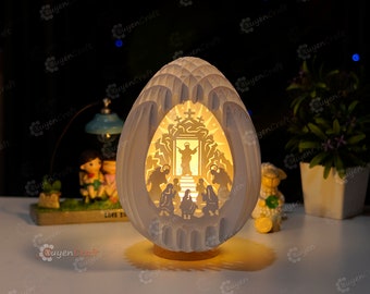 May include: A white ceramic egg-shaped lamp with a carved design depicting a religious scene. The lamp is illuminated from within, casting a warm glow on the scene. The scene depicts a group of people gathered around a doorway, with a figure standing in the doorway.