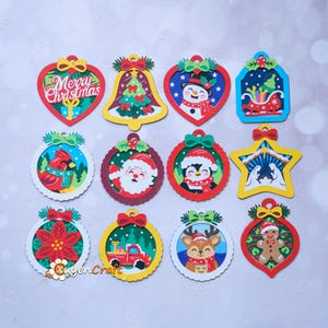 May include: A set of twelve colourful Christmas ornaments featuring various holiday designs including a heart with Merry Christmas text, a bell, a snowman, a sleigh, a cardinal, Santa Claus, a penguin, a nativity scene, a poinsettia, a truck, a reindeer, and a gingerbread man.
