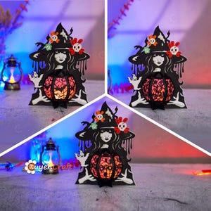 May include: A black papercraft Halloween lantern featuring a witch holding a pumpkin. The witch has long black hair and is wearing a black hat with a skull and crossbones design. The pumpkin is lit from within and has a red and orange glow.