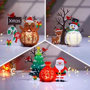 以下が含まれることがあります： クリスマスをテーマにした切り絵。プレゼントを持ったトナカイ、雪だるま、サンタクロースが描かれています。トナカイは「Xmas」の看板の近くにいます。雪だるまはシルクハットとスカーフを着用しています。