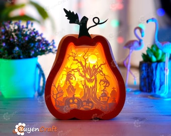 以下が含まれることがあります： ハロウィンシーンが描かれた木製のジャック・オ・ランタン型のランプ。シーンには、不気味な木、満月、墓石のある墓地が描かれています。ランプは内側から照らされ、温かい光を放っています。