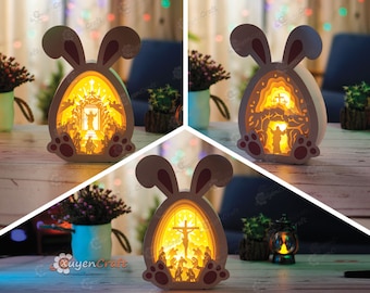 May include: Three wooden Easter bunny night lights with a 3D design. Each light features a different scene from the Easter story: the resurrection, the crucifixion, and the nativity. The lights are illuminated from within, casting a warm glow.