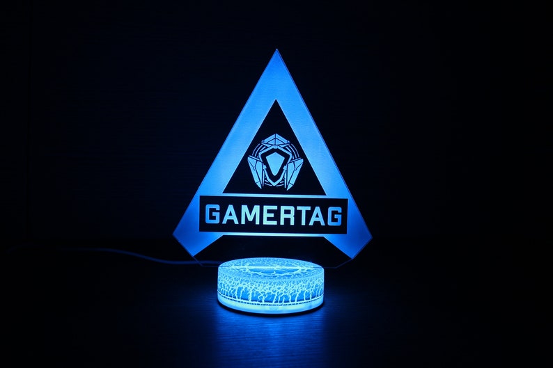 May include: A blue and white gamertag light with a triangle shape and the word "GAMERTAG" printed on it. The light is on a round base.