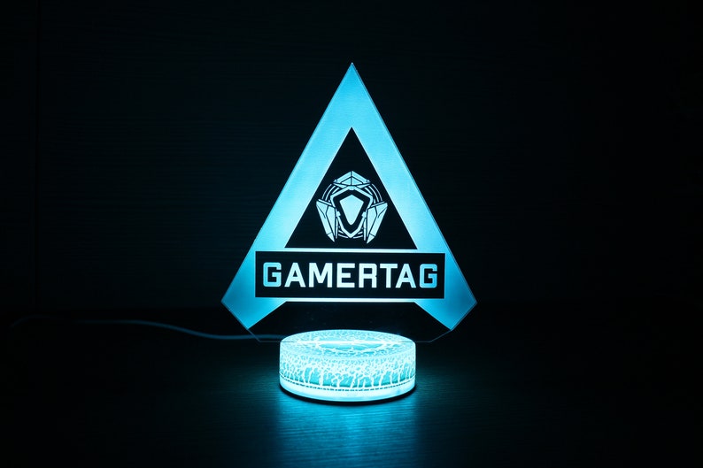 May include: A blue and white gamertag light with a triangle shape and a circular base. The light features a stylized logo and the word "GAMERTAG" in white.