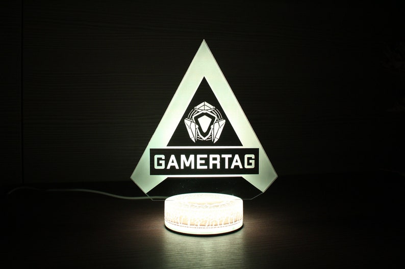 May include: A white triangular lamp with a black and white logo that says "GAMERTAG" and a white circular base.