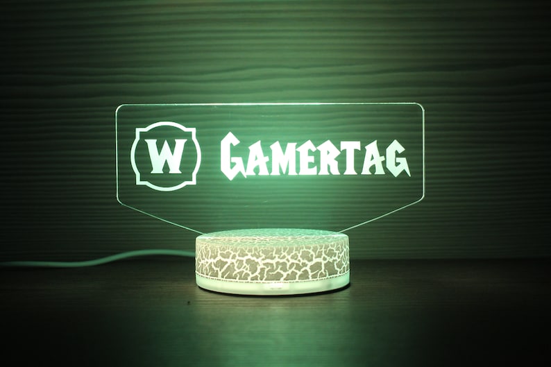May include: A green LED light with a white base and a clear acrylic panel with the text "W GAMERTAG" in white.