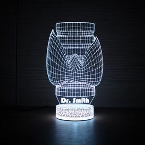 May include: A white 3D printed lamp shaped like a flower with a wireframe design. The base of the lamp has the text "Dr. Smith" printed on it.