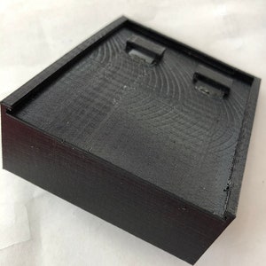 May include: A black 3D printed box with two rectangular openings on the top.