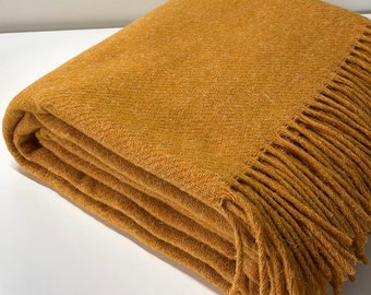 Manta 100% lana de oveja en un cálido color amarillo mostaza. Cuadros de lana beige. Funda de sofá de lana de alta calidad en color verde. Acogedora manta de cama natural en gris