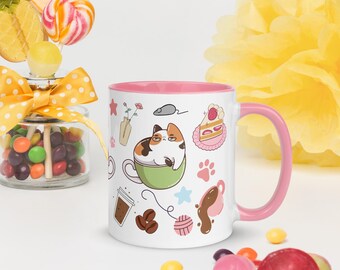 Può includere: Tazza in ceramica bianca con interno e manico rosa, con un design a cartone animato di un gatto in una tazza da tè verde. La tazza è decorata con varie illustrazioni, tra cui chicchi di caffè, una fetta di torta e impronte di zampe. Caramelle e un fiore giallo sullo sfondo.