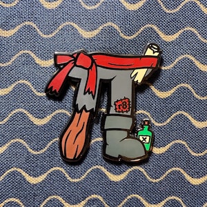 Könnte beinhalten: Eine graue und rote Emaille-Anstecknadel mit einem Piratenbein, einem roten Bandana, einer Flasche Rum und der Nummer "18" auf dem Bein.