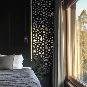 Modern bedroom with black accent wall, geometric room divider, and floor-to-ceiling windows overlooking greenery.