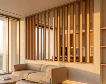 Könnte beinhalten: Ein modernes Wohnzimmer mit einem beigen Sofa, einem runden Couchtisch und einem hellen Teppich. Eine Holzlattenwand dient als Raumteiler, und ein großes Fenster bietet einen Blick nach draußen. Der Raum ist von warmem Sonnenlicht durchflutet.